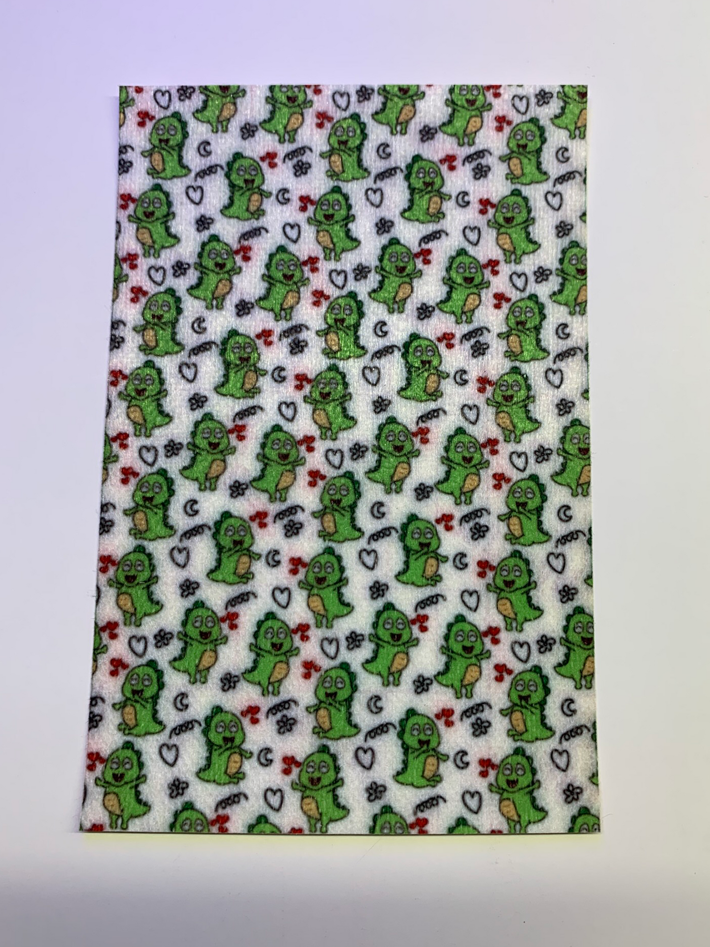 4x6" tubie tape featuring a white background with small green cartoon dinosaurs in a repeating pattern. Includes hearts, stars, and playful doodle accents in black and red. Fun, whimsical, and kid-friendly design.
