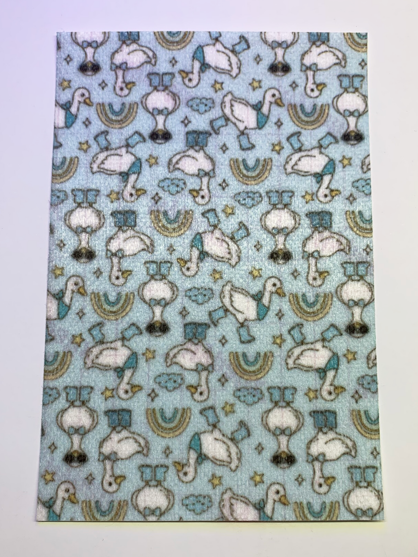 4x6" tubie tape featuring a light blue background with white geese wearing blue boots and hats in a repeating pattern. Includes small stars, clouds, and rainbow shapes in soft muted tones. Playful, whimsical, and nursery-inspired design.