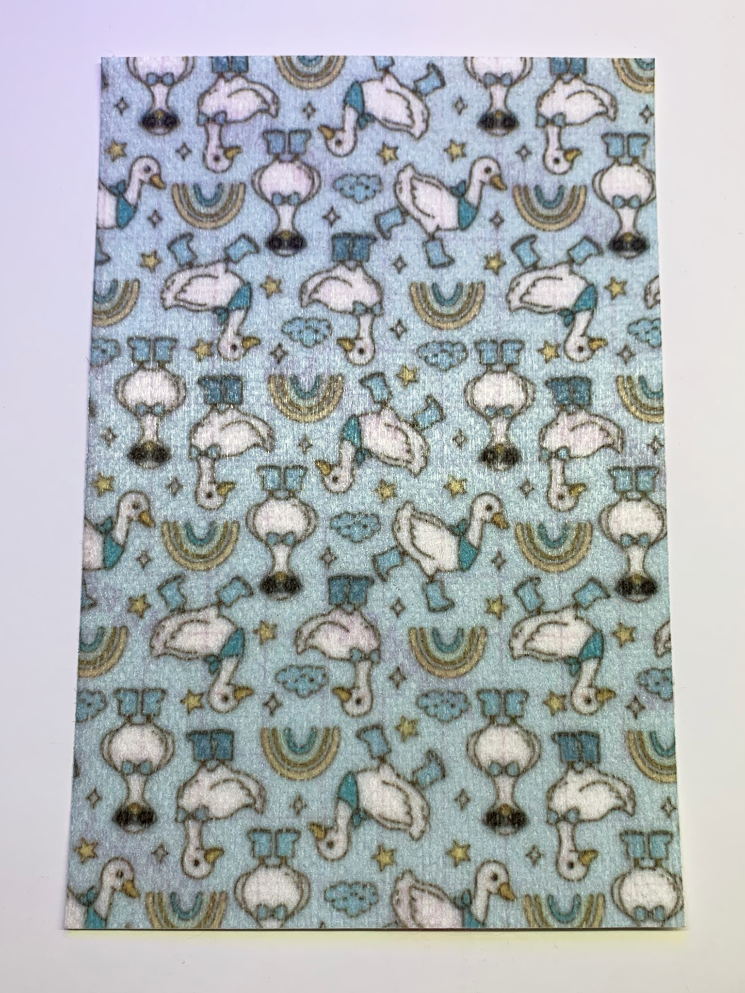 4x6" tubie tape featuring a light blue background with white geese wearing blue boots and hats in a repeating pattern. Includes small stars, clouds, and rainbow shapes in soft muted tones. Playful, whimsical, and nursery-inspired design.