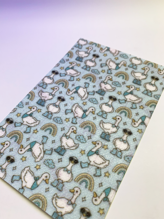4x6" tubie tape featuring a light blue background with white geese wearing blue boots and hats in a repeating pattern. Includes small stars, clouds, and rainbow shapes in soft muted tones. Playful, whimsical, and nursery-inspired design.