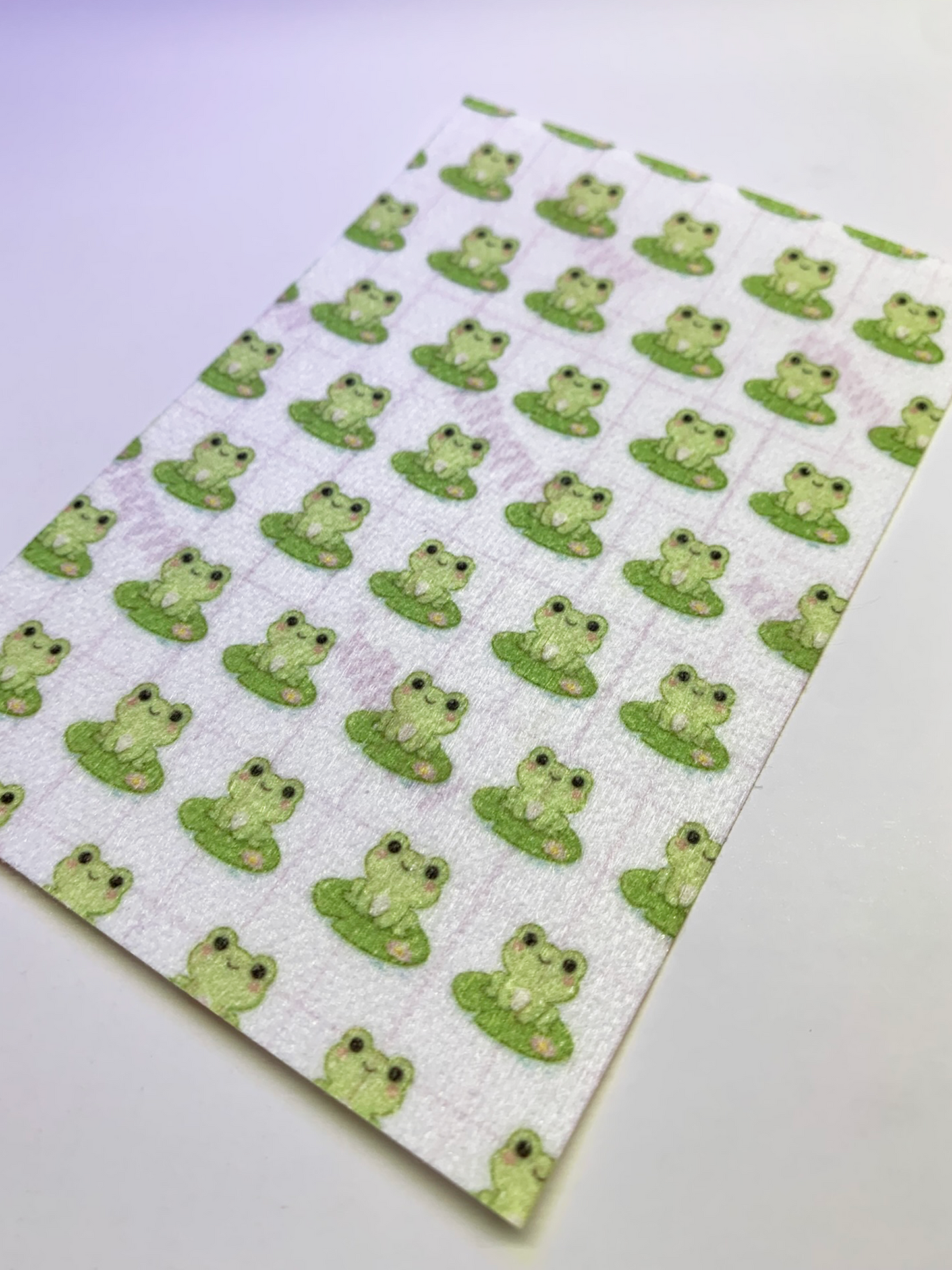 4x6" tubie tape featuring a soft light background with small green frogs sitting on lily pads in a repeating pattern. Each frog has simple black eyes and a cute expression. Minimal, playful, and nature-inspired design.
