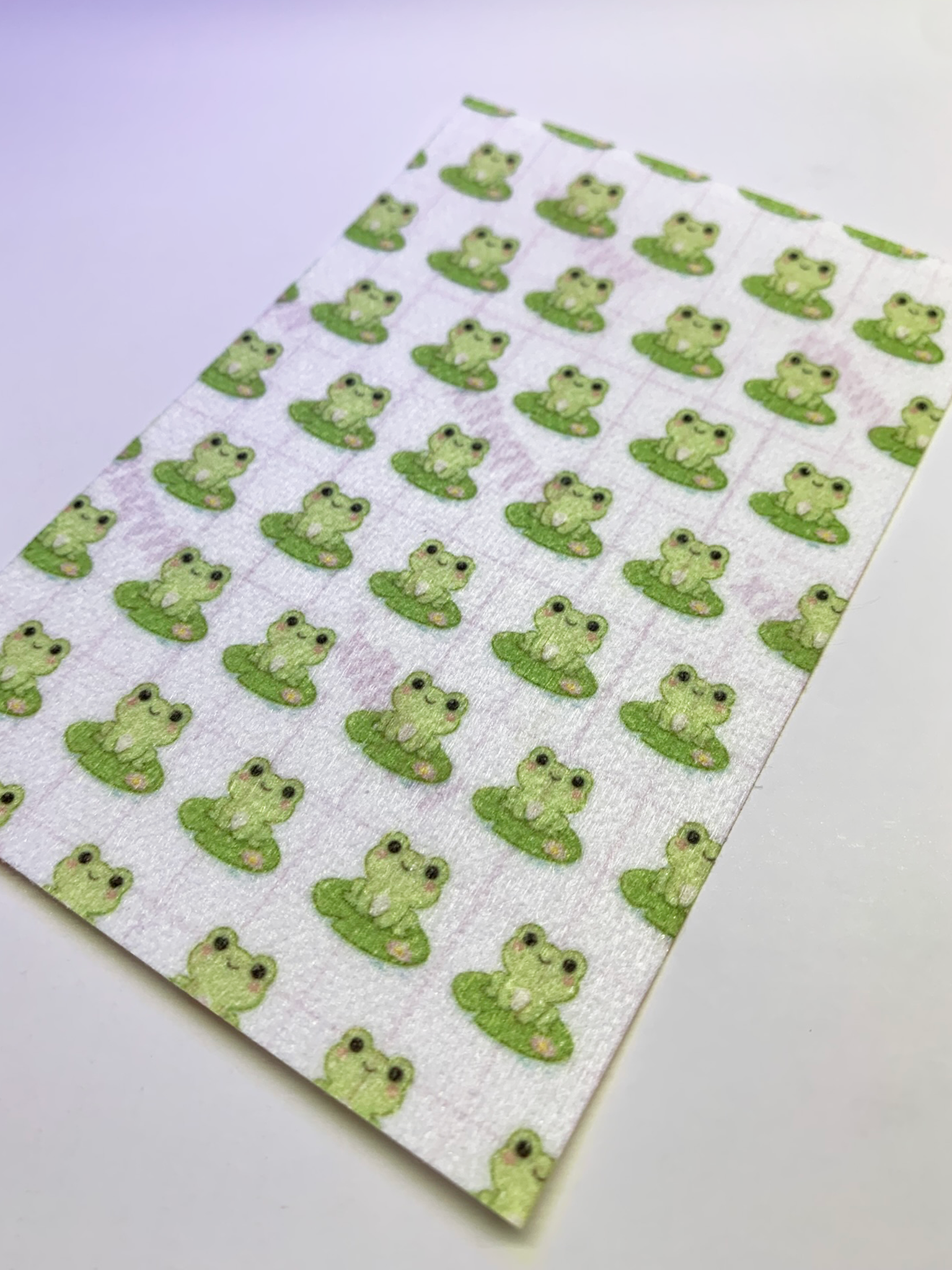 4x6" tubie tape featuring a soft light background with small green frogs sitting on lily pads in a repeating pattern. Each frog has simple black eyes and a cute expression. Minimal, playful, and nature-inspired design.
