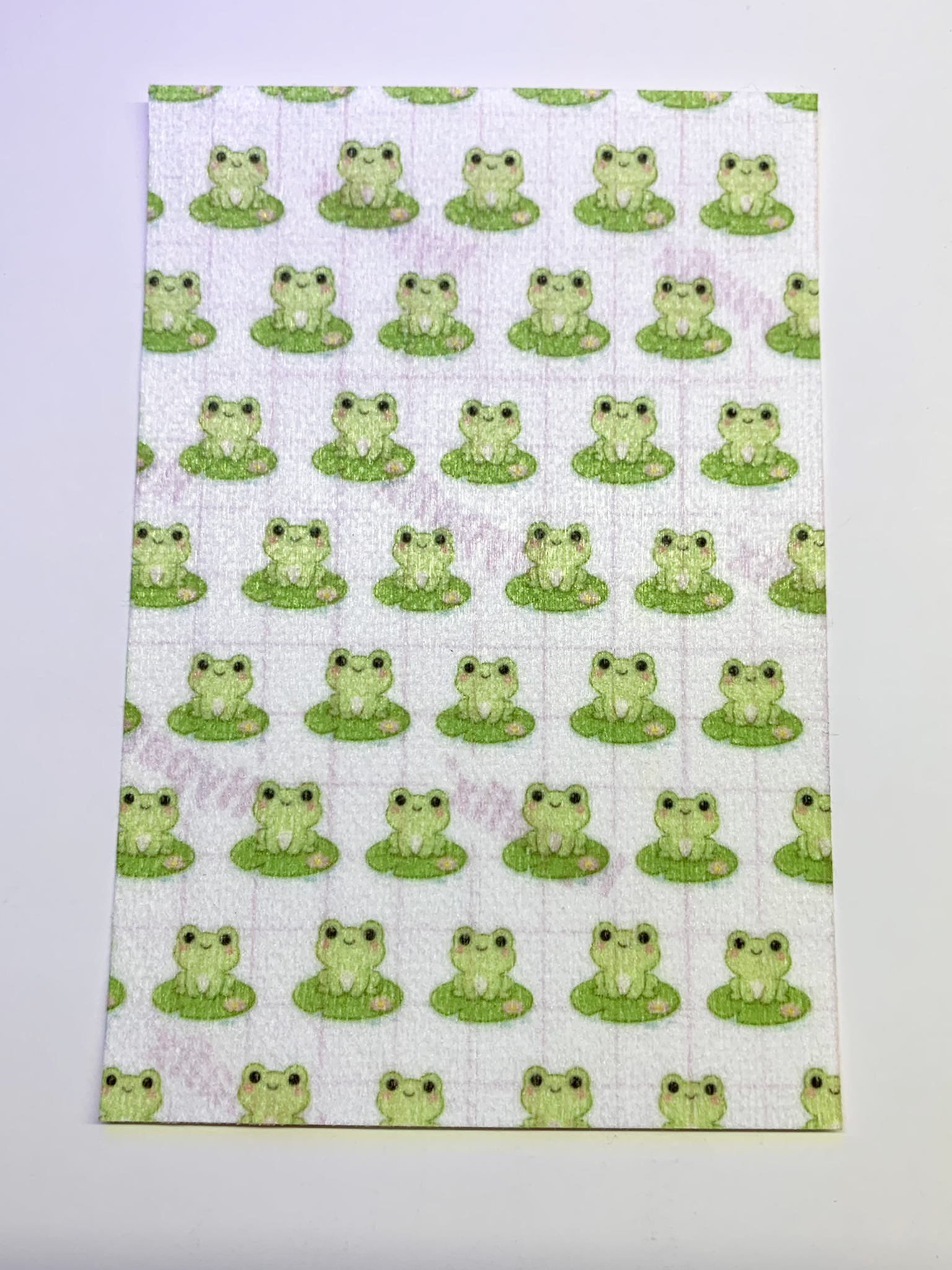 4x6" tubie tape featuring a soft light background with small green frogs sitting on lily pads in a repeating pattern. Each frog has simple black eyes and a cute expression. Minimal, playful, and nature-inspired design.
