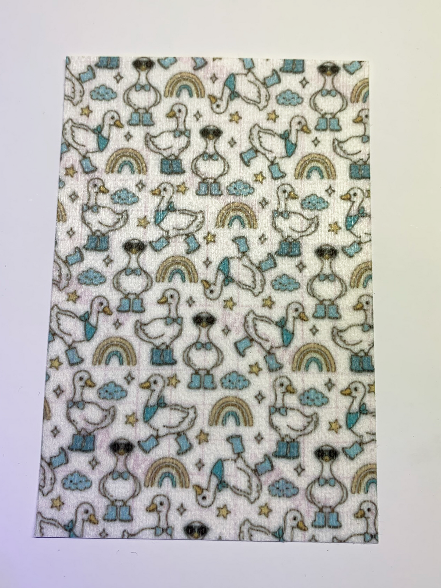 4x6" tubie tape featuring a white background with geese wearing blue boots and bow ties in a repeating pattern. Includes rainbows, clouds, and stars in soft neutral tones. Cute, playful, and whimsical design.
