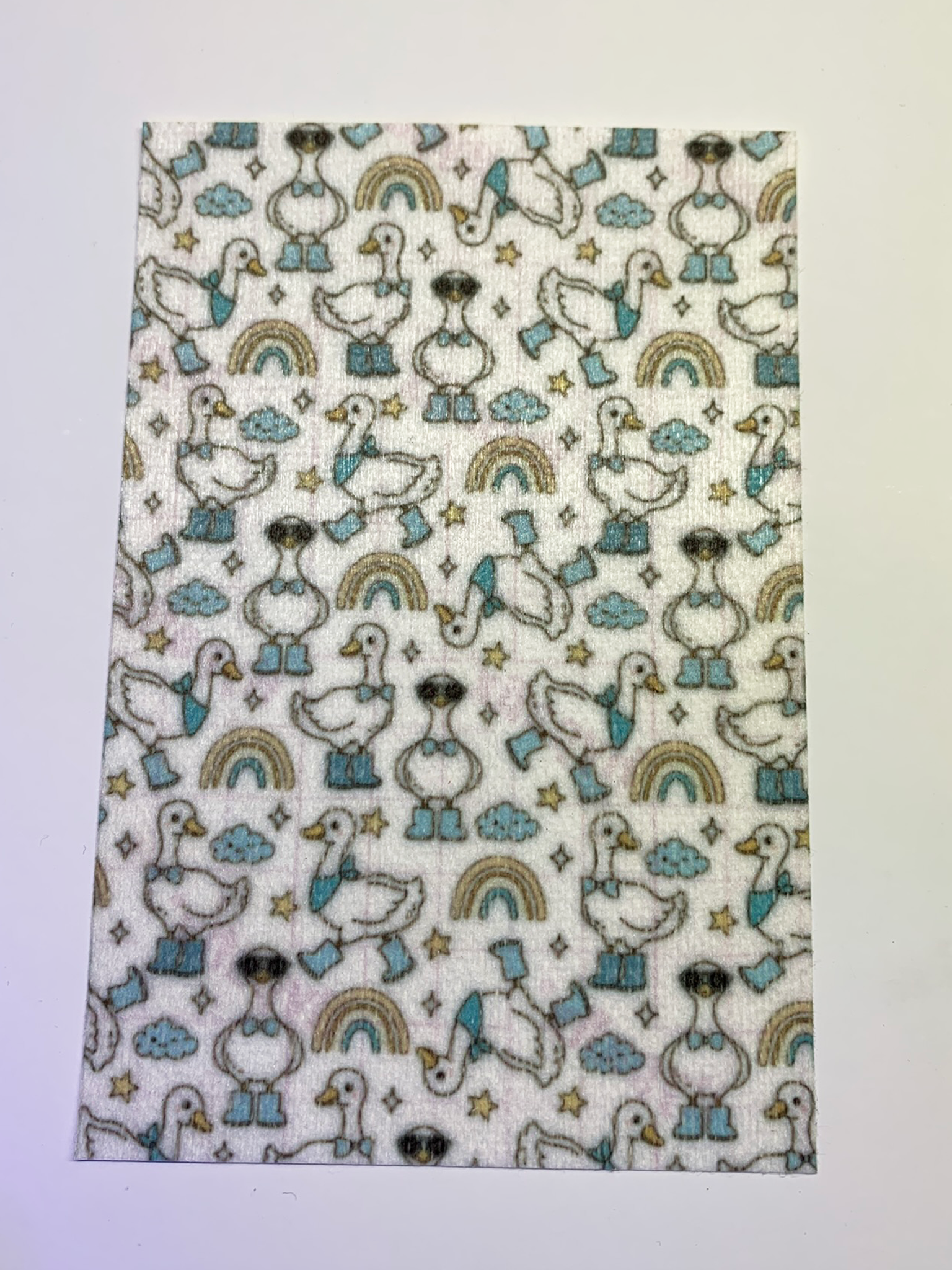 4x6" tubie tape featuring a white background with geese wearing blue boots and bow ties in a repeating pattern. Includes rainbows, clouds, and stars in soft neutral tones. Cute, playful, and whimsical design.
